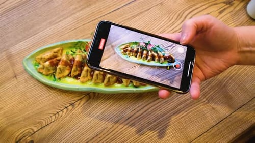 Girl Blogger Shoots a Dish with Food on Her Smartphone