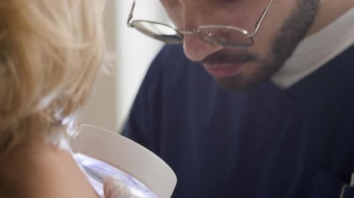 Young Male Dermatologist Examining Moles with Magnifying Glass