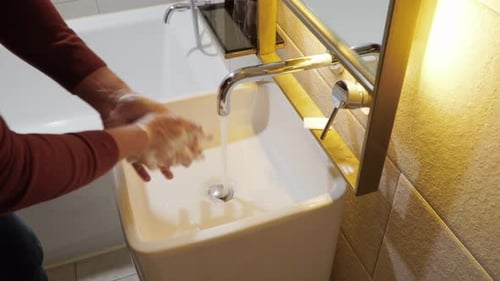 Carefully washing hands in a bathroom sink with soap and hot water - concept: COVID prevention, dise