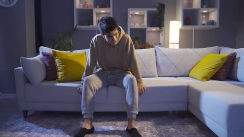 The man sits on the ground in despair and anguish. Worried, hopeless man.