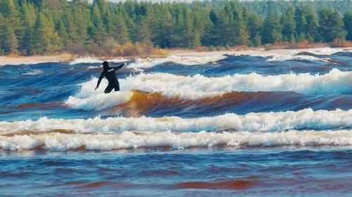 Surfing in Russia. Man in black wetsuit surfs the windy wave on Ladoga Lake in Russia