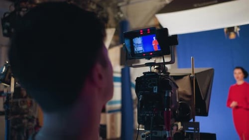 Cameraman Filming Presenter During Studio Shoot with Blue Screen Background