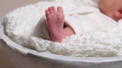 Bare Feet of Newborn Baby in White Blanket