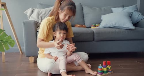 mom trimming fingernails of kid sit on floor in living room at house.