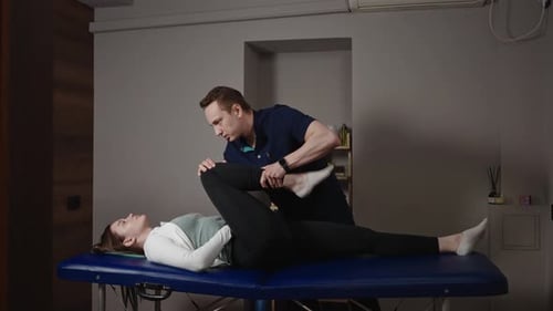 A Male Osteopath Performs Physical Therapy on a Female Patient The Doctor Looks at the Condition of