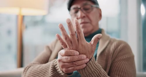Elderly man, hands and sofa with arthritis, ache or joint pain from fibromyalgia