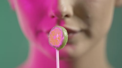 Gros plan du visage et de la bouche d'une femme, suçant et léchant des bonbons à la sucette, photo de studio colorée