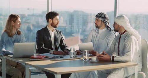 Four Business People Caucasian Couple Managers and Two Arabian Businessmen Signing Up Contract for