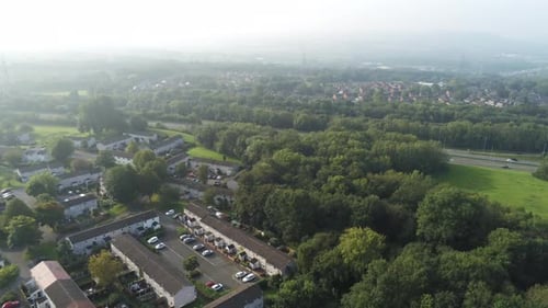 Urban aerial view looking down over park suburbs homes townscape panning right