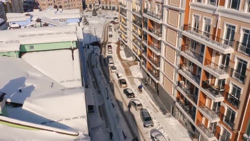 Aerial Winter Top View of Modern City Center with High Apartment Buildings and Parked Cars on Snowy
