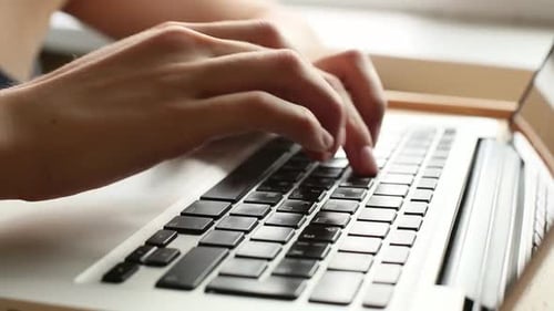 Synergy Collection: Side view close-up of hands typing over a laptop keyboard