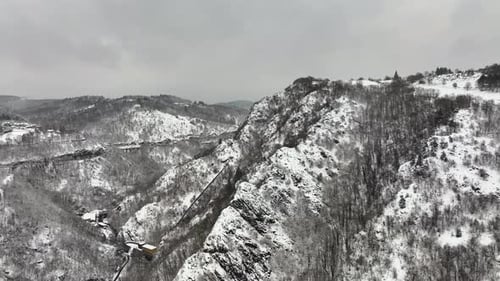 Aerial Foggy Landscape with Mountain Cliffs Covered with Fresh Fallen Snow During Heavy Snowfall in
