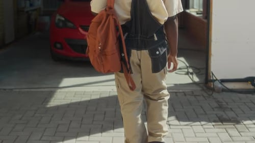 Un mecánico negro llega al garaje con un coche rojo