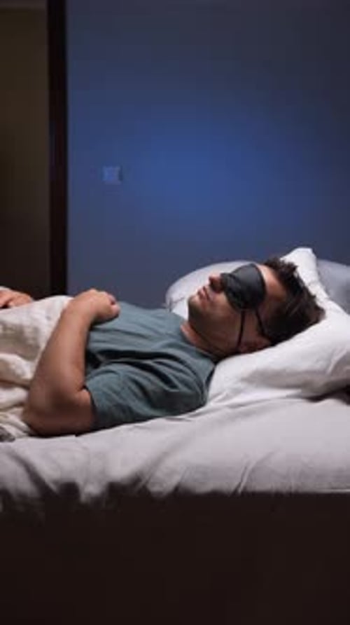 Vertical Video Man Sleeping Peacefully in Bed Wearing Sleep Mask