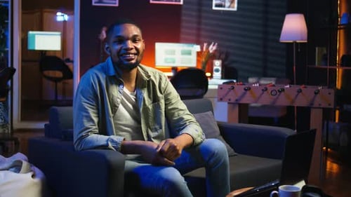 Retrato de una persona afroamericana sonriendo y trabajando en su sala de estar