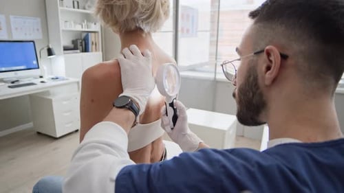 Dermatologist Examining Female Patients Skin on Back with Magnifying Glass