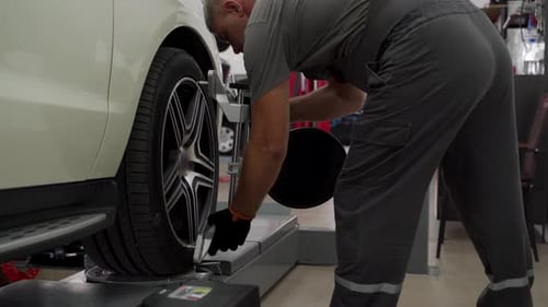 Auto Mechanic Adjusts Car Wheel Alignment with Precision Equipment in Garage Professional Tech