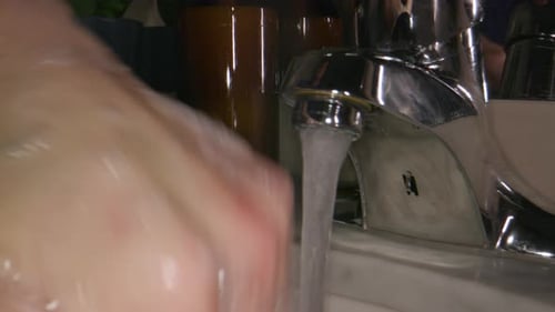 Close up of proper handwashing technique in a moody-lit bathroom