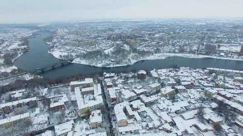 Twisted river diving the big city into two parts. Urban panorama on the cold gloomy snowy winter day