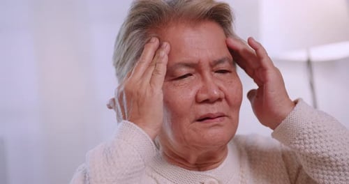 Anciana asiática con migraña. Mujer mayor que sufre de dolor de cabeza.