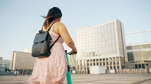 A Modern Girl Rides Around the City in the Sunset Rays of the Sun