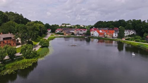 Drone Glides Over Peaceful Talsi Lake, Surrounded by Colorful Buildings