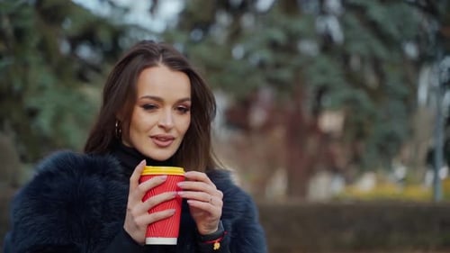Happy woman drinking cup of coffee in the street