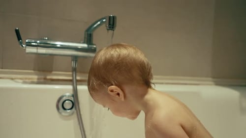 Süßer kleiner Junge legt den Kopf unter Wasser und rennt aus dem Wasserhahn