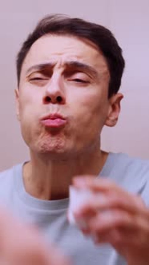 Man Rinsing Mouth with Mouthwash in Bathroom Mirror