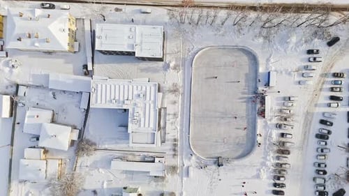 Birds eye drone shot over a game at a urban ice hockey rink, sunny, winter day
