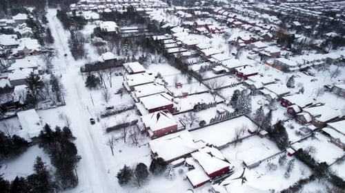 Residential suburban neighborhood with rooftops covered in snow aerial fly over winter snow storm