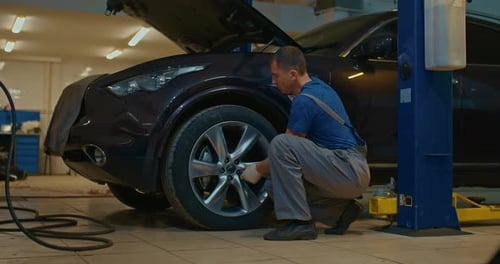 Auto Mechanic Tightens the Bolts at the Car Service Station