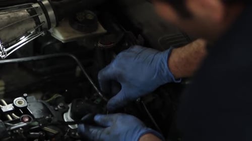 mechanical hands on blue gloves repairing some parts of a car in the garage