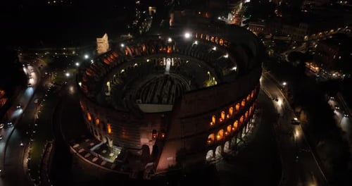 Aerial fly drone view of Colosseum or Coliseum at night, Rome, Italy, Europe. Ancient Roman ruin is