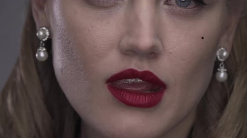 Gros plan d'une femme blonde avec du rouge à lèvres rouge se mordant la lèvre, 4k