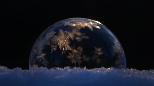 Soap Bubble on Snow Freezing in Cold Winter on Black Background