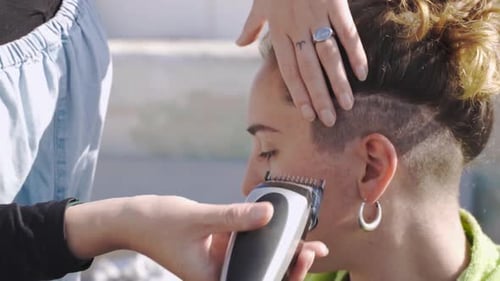 Cinematic slow motion shot of a barber fading the sides on a female customer
