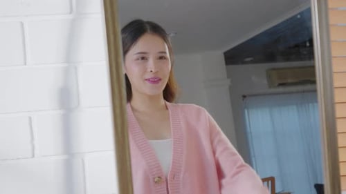 Belle jeune femme asiatique regarde le miroir, dégageant fierté et confiance, reflet de soi