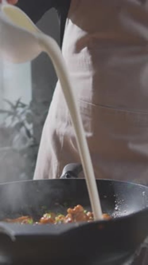 Homem irreconhecível adicionando creme à panela, completando o prato