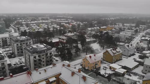 Aerial pull out landscape view of a small rural town with houses and homes covered with snow, winter