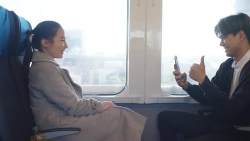 4K Asian couple using mobile photography together during travel on train.
