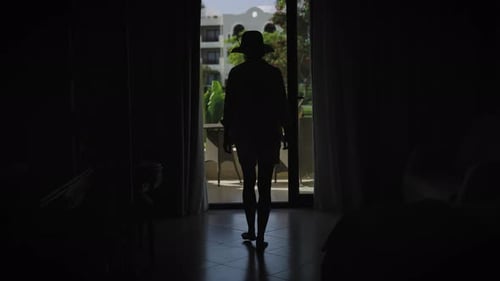 A Slender Young Woman Dressed in Summer Attire Wearing a Hat and Sunglasses Steps Out of Her Room