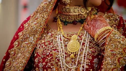 The Bride is Dressed in Traditional Red Asian Clothes with Beautiful Neckless on Her Neck Elements