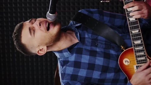 Singer sings lyrical composition into microphone at studio. Vertical video