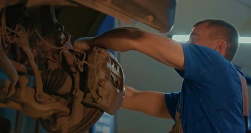 Mechanic Technician Works on Repairing the Chassis of a Car in a Garage a Vehicle Inspection Station