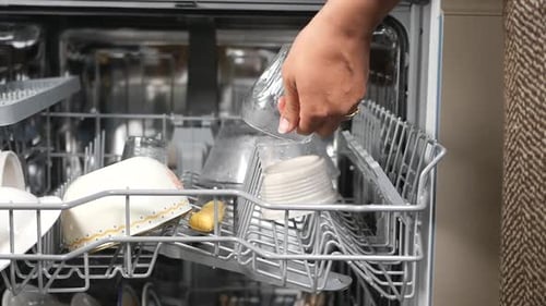 Carefully Placing the Glass Into Dishwasher Surrounded By Clean Dishes