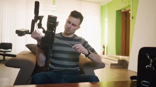 Studio Guy Holding Camera with Microphone Attached Focusing on Lens