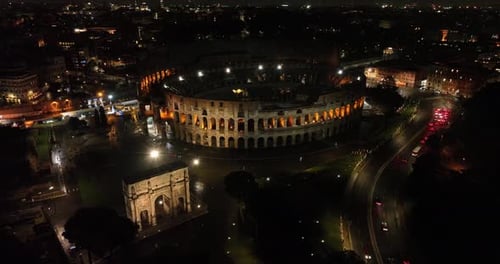 Aerial fly drone view of Colosseum or Coliseum at night, Rome, Italy, Europe. Ancient Roman ruin is