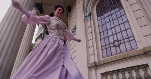 An Elegant Woman in a Vintage Dress Stands By an Old Stone Column