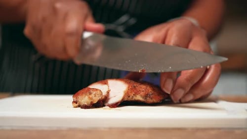 Slicing pan-fried boneless chicken breast for a homemade meal - slow motion